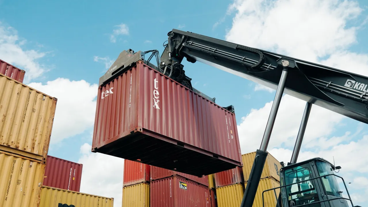 Reachstacker hebt einen Container im Terminal Kapfenberg vor blauem Himmel