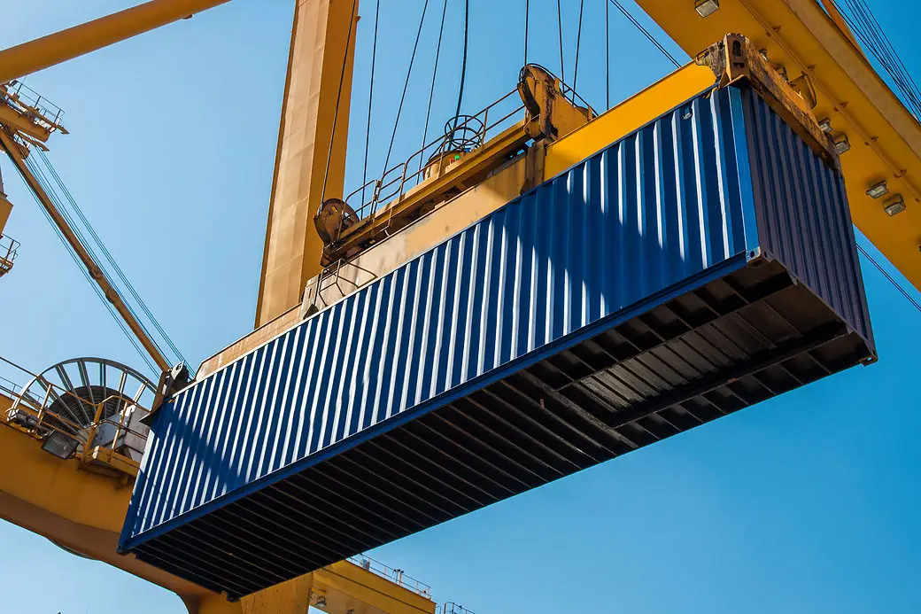 Portalkran hebt einen Container über dem Terminal